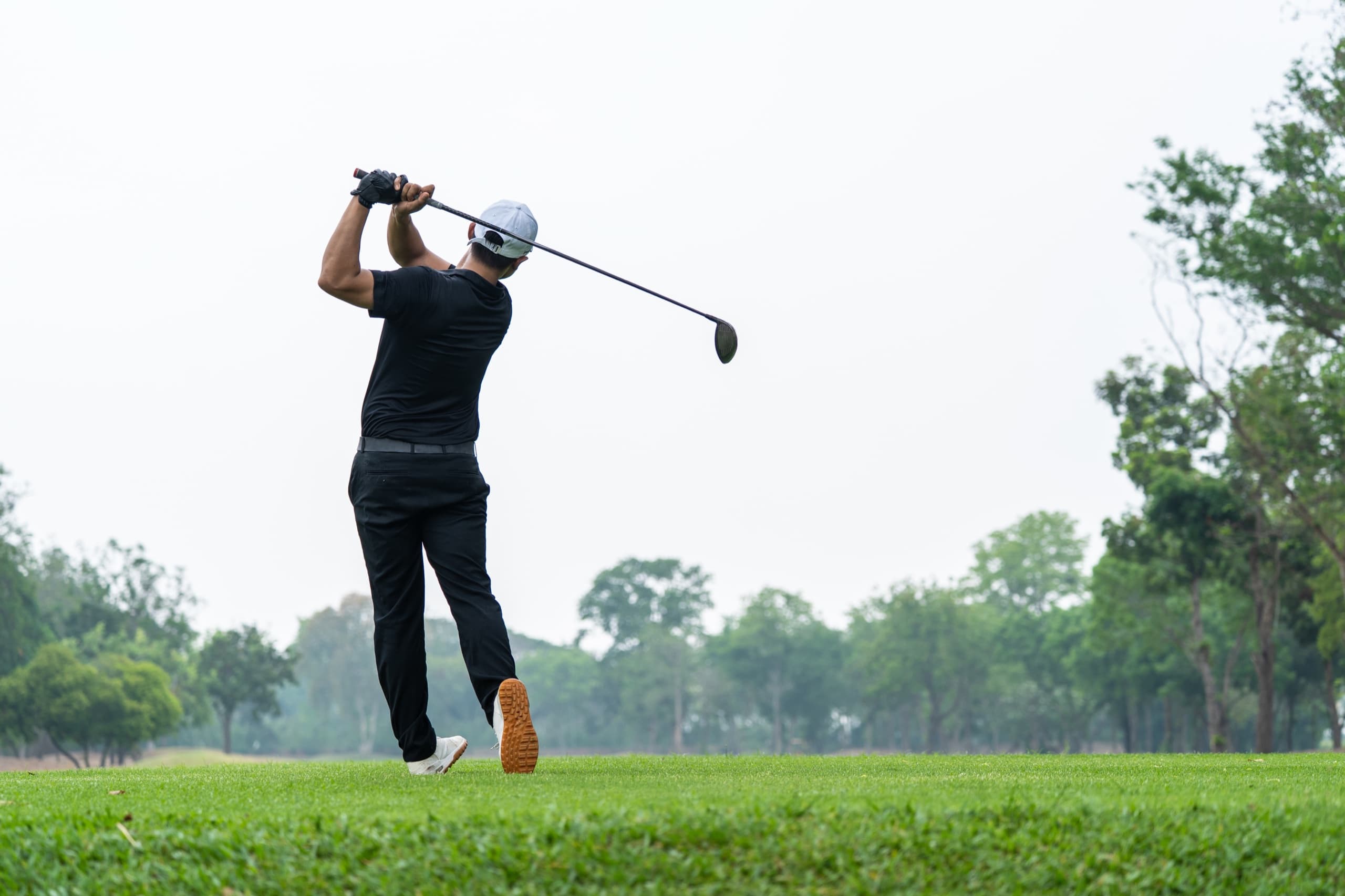 Golfer mid-swing on an open fairway